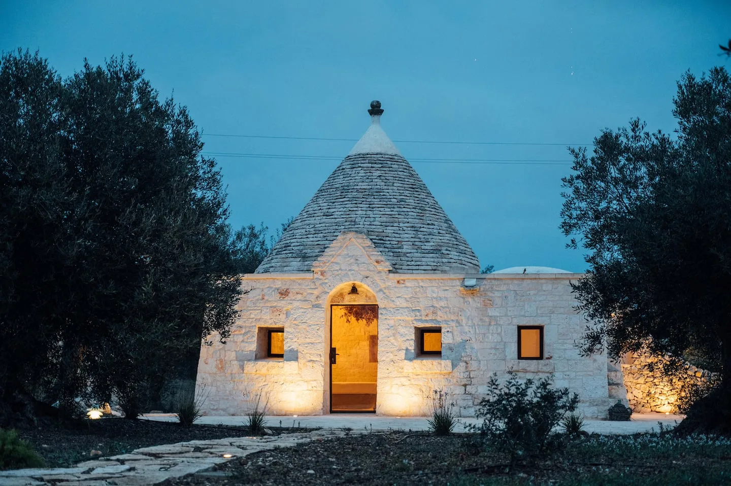 Stone trullo and olive trees at blue hour