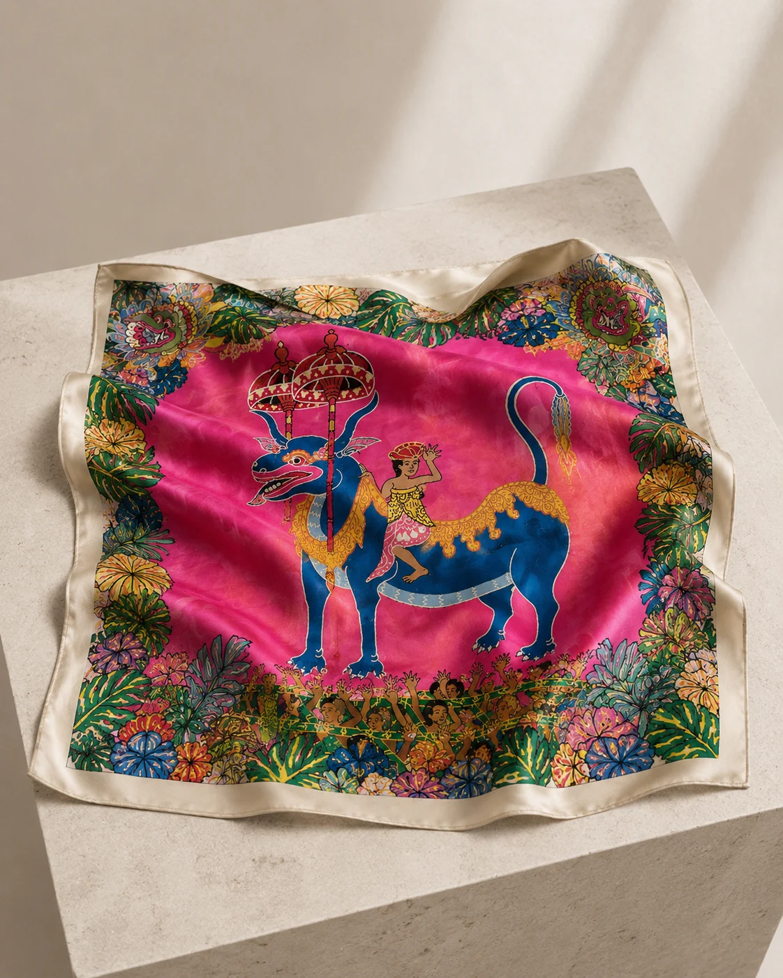 Pink square silk with blue dragon procession artwork arranged on a pale stone plinth
